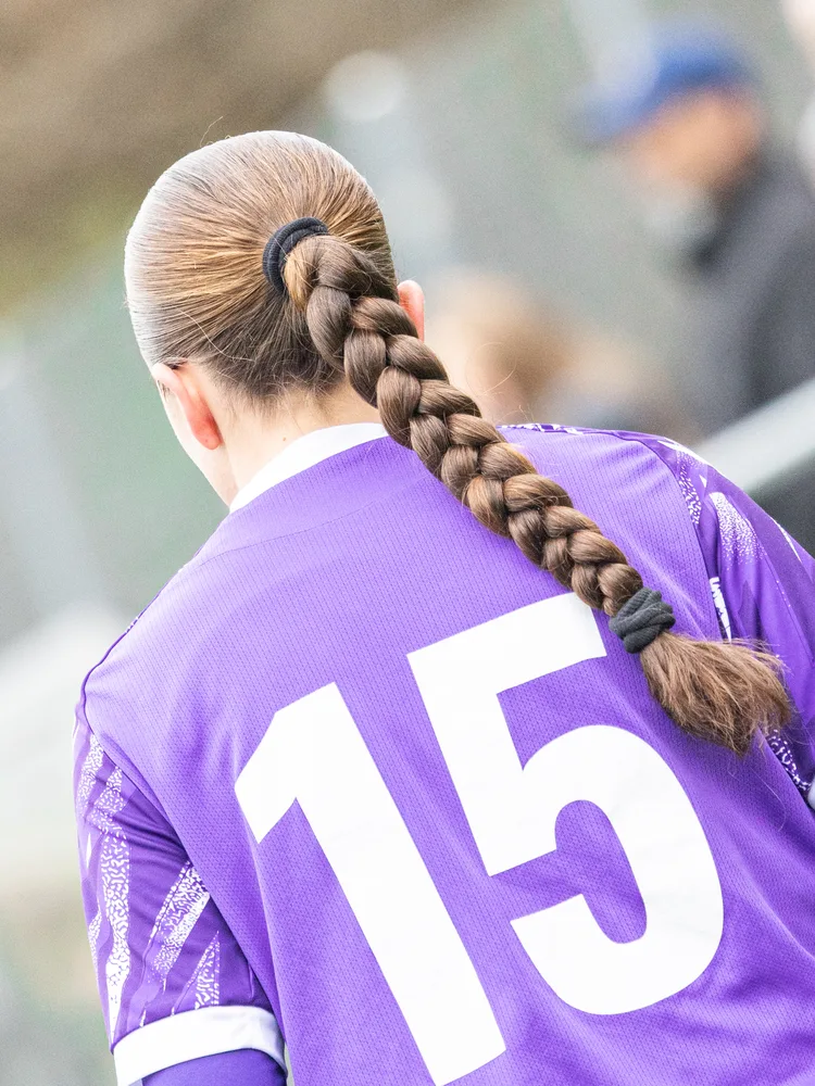 Une joueuse de l'équipe féminine vue de dos, tresse et numéro 15